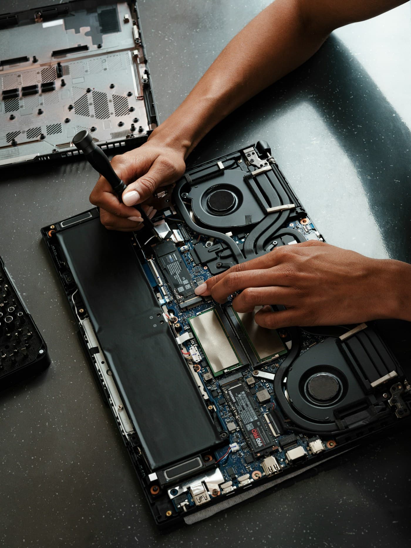 Technician repairing an opened laptop with a screwdriver